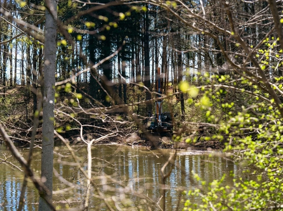 Foreuse sur chenilles en forêt, positionnée en bordure d'un plan d'eau