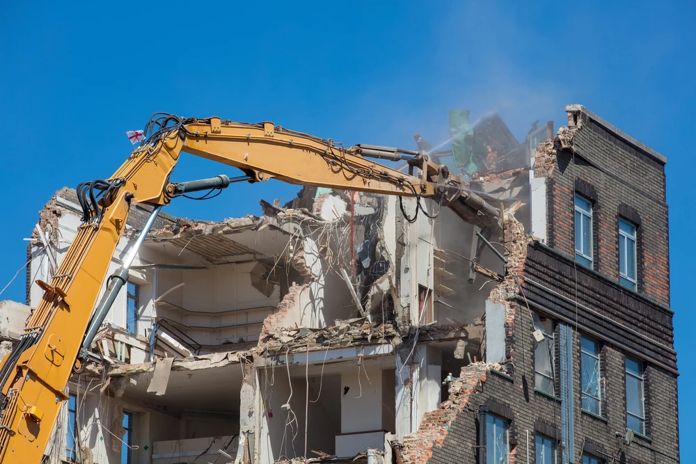 Chantier extérieur avec opérateur conduisant une mini-pelle en activité de terrassement près d'une construction en bois