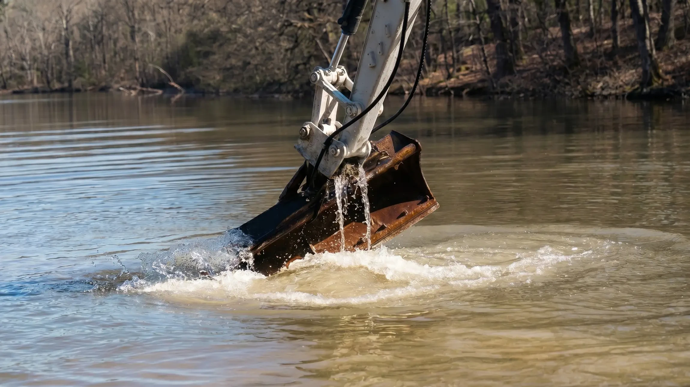 Ouvrier en combinaison rouge travaillant dans un bassin de rétention d'eau, utilisant un équipement de pompage industriel avec câbles électriques orange